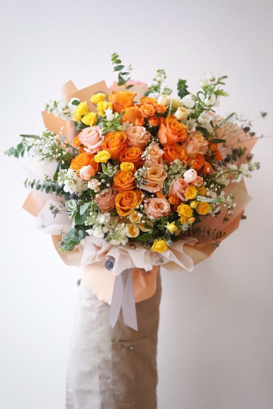 Orange, peach and yellow roses with eucalyptus and white blooms