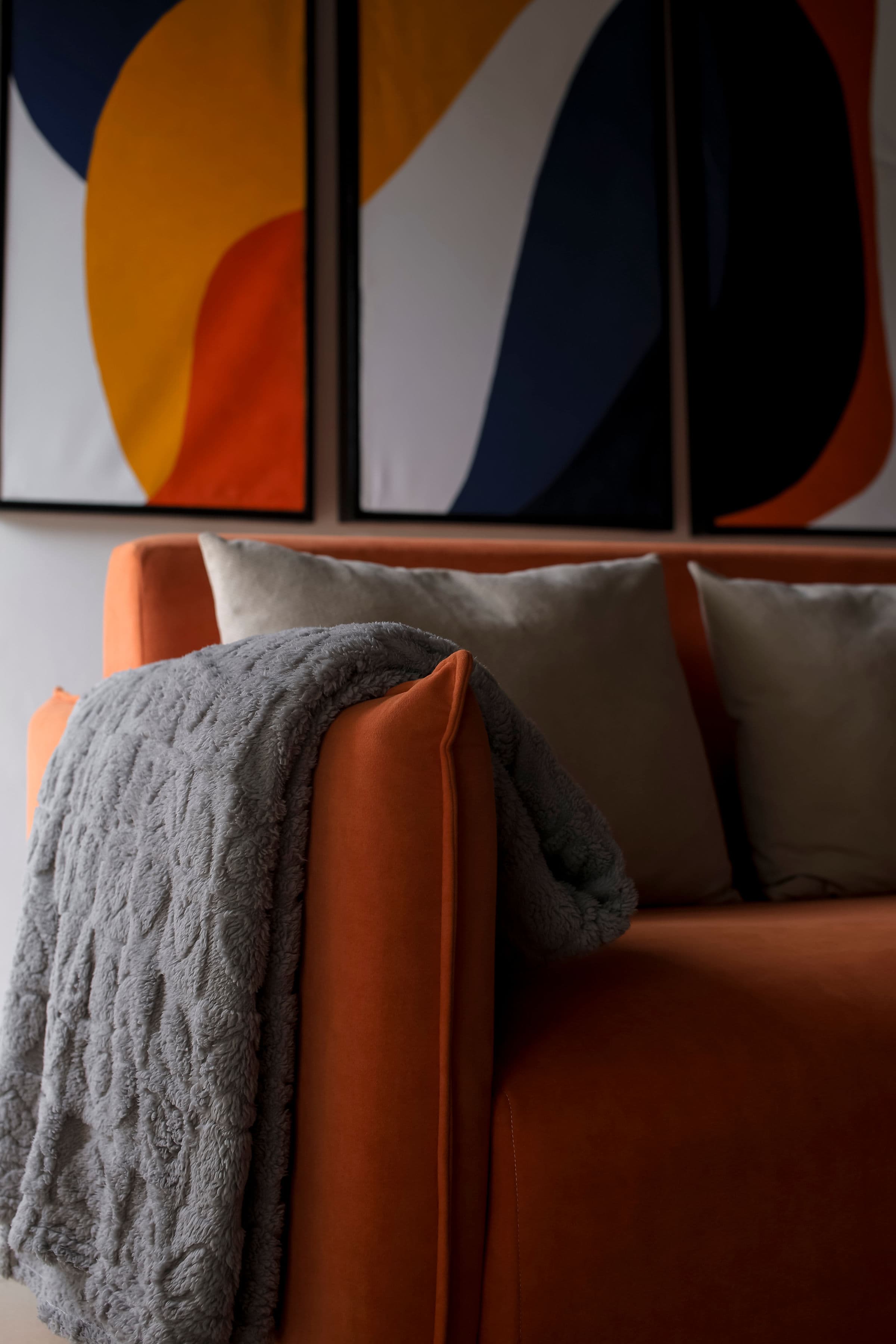 Velstays — the orange sofa, a soft blanket thrown over the arm
